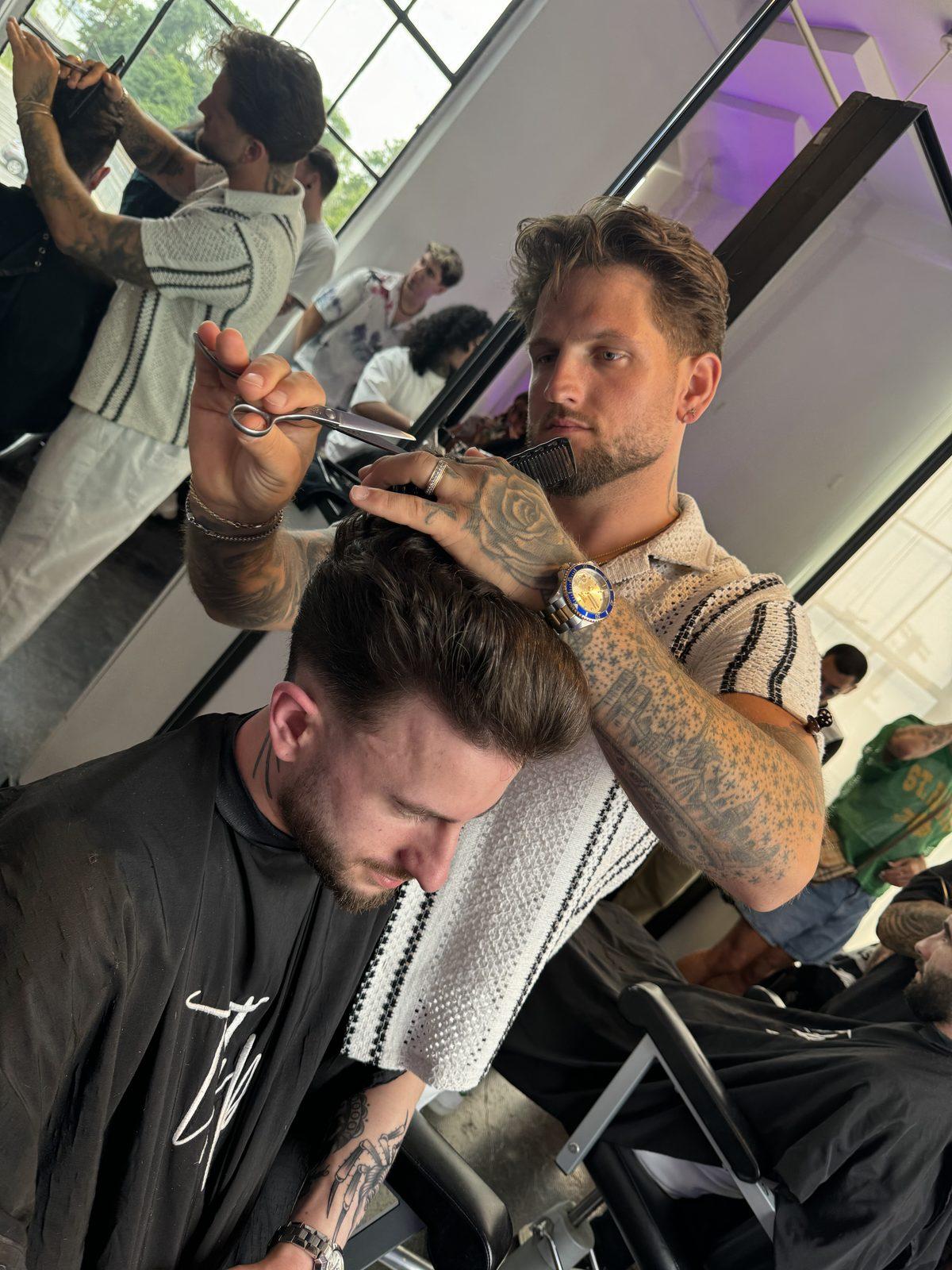 Joey DeCollibus cutting a client's hair with shears and comb at Ascension Barber Studio.